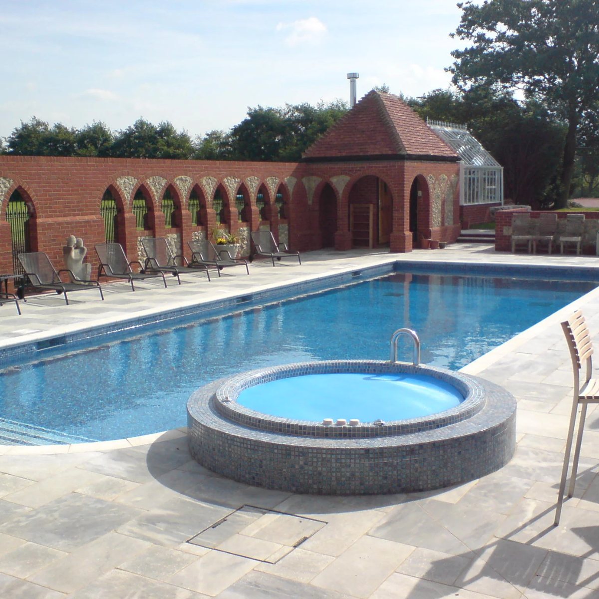 Outdoor pool with adjoining raised mosaic-tiled spa