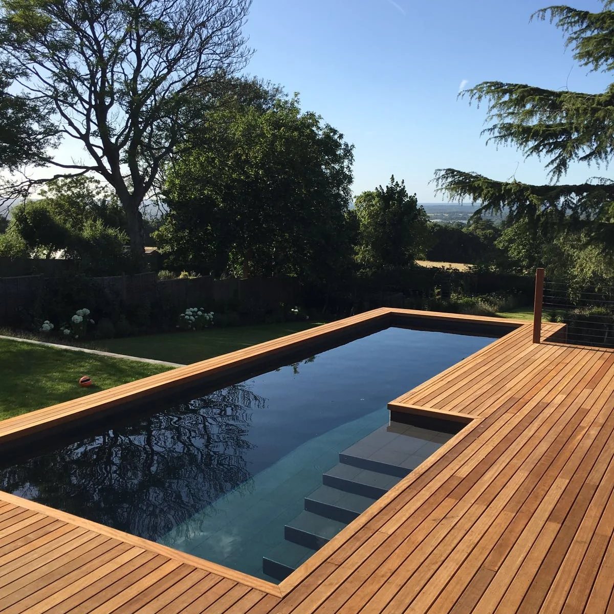 Contemporary outdoor pool framed by hardwood decking with countryside views